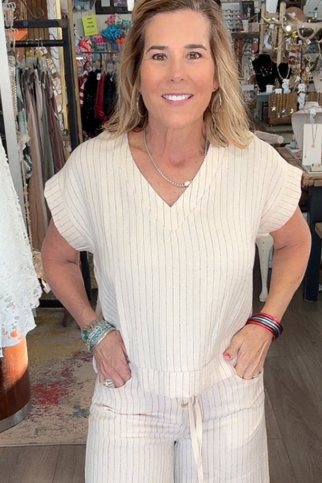 Woman in a white outfit standing in a store with various items in the background