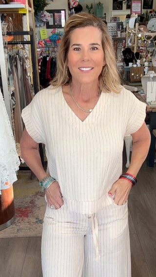 Woman in a white outfit standing in a store with various items in the background