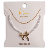 Pearl necklace with a gold bow pendant on a 'klari necklaces' card.