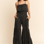Woman wearing a black tiered jumpsuit on a beige background