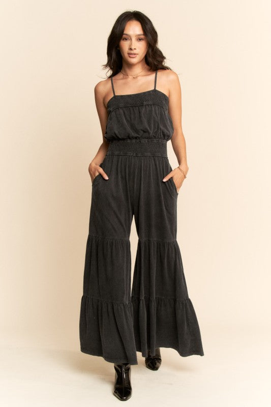 Woman wearing a black tiered jumpsuit on a beige background