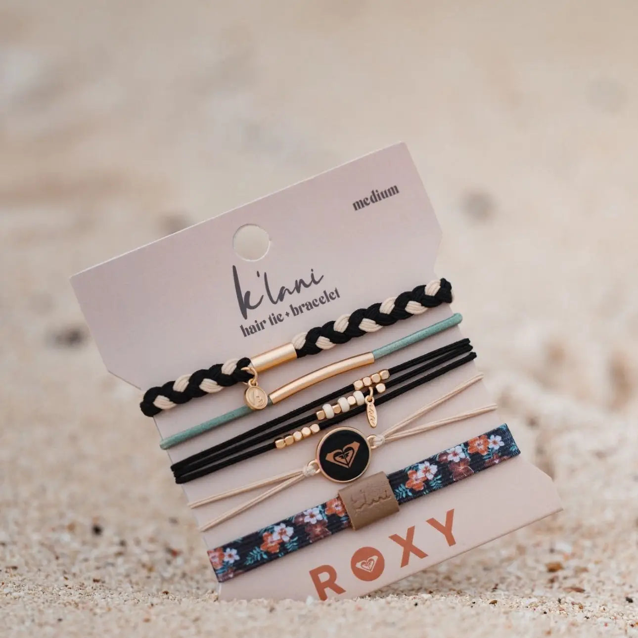 Set of hair ties and bracelets on a sand background