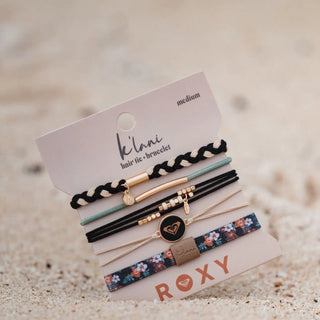 Set of hair ties and bracelets on a sand background