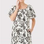 Woman wearing a black floral dress on a light gray background