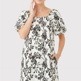 Woman wearing a black floral dress on a light gray background