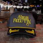 Black and yellow cap with 'High Falutin' text on a wooden surface in a bar setting