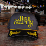Black and yellow cap with 'High Falutin' text on a wooden surface in a bar setting