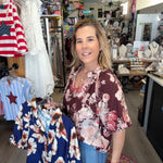 Woman standing in a store with clothing racks and American flag in the background