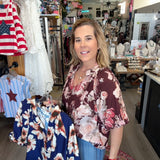 Woman standing in a store with clothing racks and American flag in the background