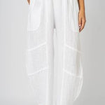 A pair of white linen pants with flat front pockets and details on the knee area. The pants are made in Italy.