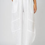 A pair of white linen pants with flat front pockets and details on the knee area. The pants are made in Italy.