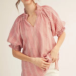 Woman wearing a red and white checkered blouse with ruffled sleeves on a plain background