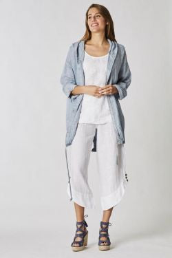 Woman wearing a light blue jacket and white pants on a plain background