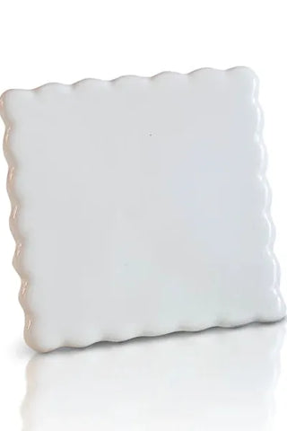 White decorative pillow with scalloped edge on a white background