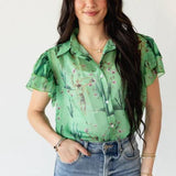 Woman wearing a green floral blouse and blue jeans on a white background