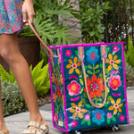 Colorful floral-patterned bag with wheels being pulled by a person outdoors.