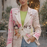 Woman wearing a patterned jacket with a design of a woman's face and the number 5, standing outdoors.