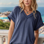 Woman wearing a blue textured top and jeans with a scenic background