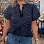 Person wearing a navy blue patterned top and jeans in an indoor setting