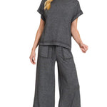 Woman wearing a gray outfit with wide-leg pants on a white background