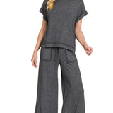 Woman wearing a gray outfit with wide-leg pants on a white background
