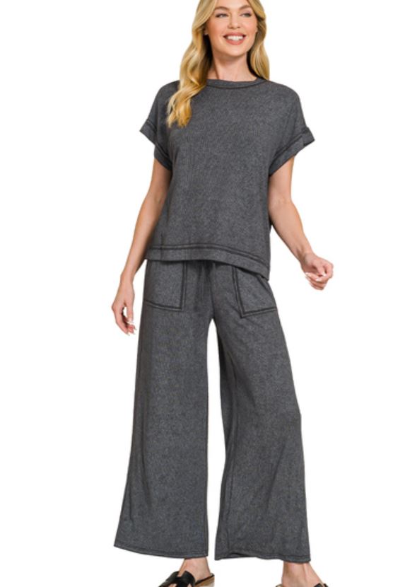 Woman wearing a gray outfit with wide-leg pants on a white background