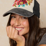 Woman wearing a colorful floral embroidered cap on a beige background