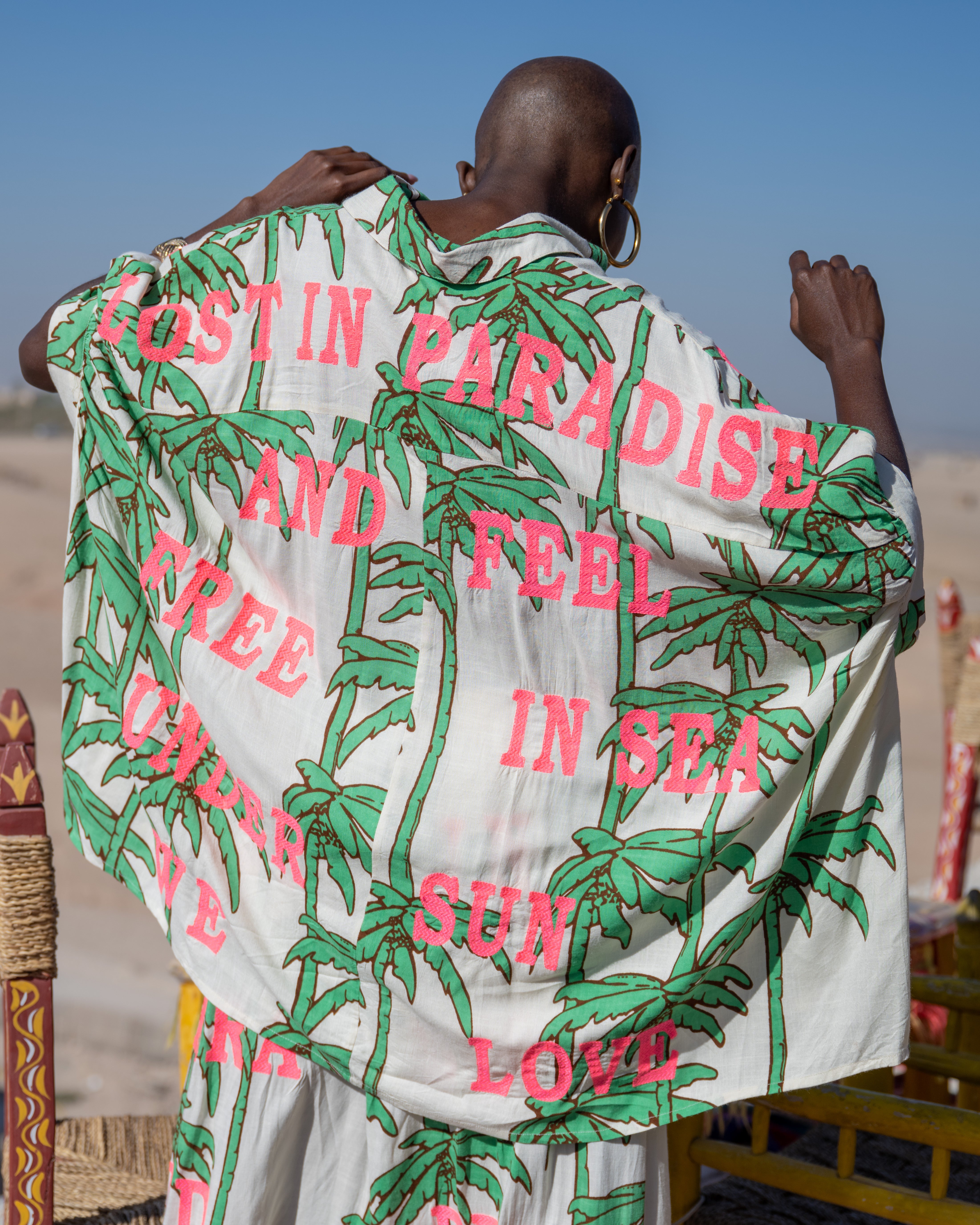 Person wearing a patterned garment with text in a desert setting