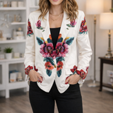 Woman wearing a white blazer with colorful floral patterns in an indoor setting.