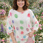 Woman wearing a colorful polka dot sweater in a garden setting