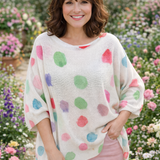 Woman wearing a colorful polka dot sweater in a garden setting