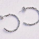 Silver hoop earrings with beaded design on a light gray background