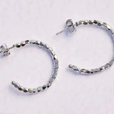 Silver hoop earrings with beaded design on a light gray background