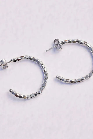 Silver hoop earrings with beaded design on a light gray background