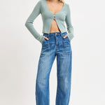 Woman wearing a light blue cardigan and blue jeans on a white background