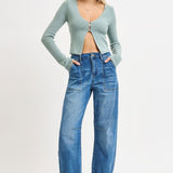 Woman wearing a light blue cardigan and blue jeans on a white background