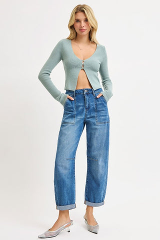 Woman wearing a light blue cardigan and blue jeans on a white background