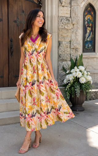 Woman in a floral dress standing outside a building with a stained glass window.