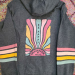 Gray hoodie with colorful design on the back against a patterned fabric background