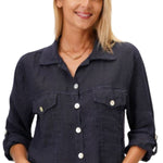 A woman smiling and wearing a navy blue linen crop jacket with a collar, button-up front, and two front pockets. She is also wearing blue jeans.