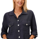 A woman smiling and wearing a navy blue linen crop jacket with a collar, button-up front, and two front pockets. She is also wearing blue jeans.