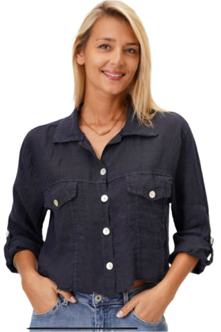 A woman smiling and wearing a navy blue linen crop jacket with a collar, button-up front, and two front pockets. She is also wearing blue jeans.