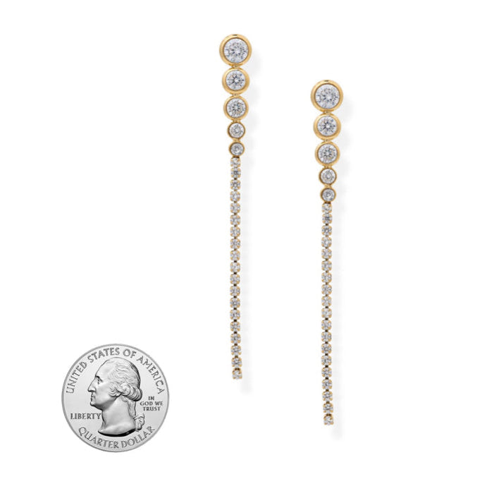 Pair of gold and diamond earrings on a white background with a quarter coin for scale.