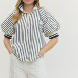 Woman wearing a striped shirt and white pants on a plain background