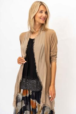 Woman wearing a beige cardigan over a black dress with colorful patterns on a white background