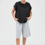 Person wearing a black t-shirt and gray shorts on a white background