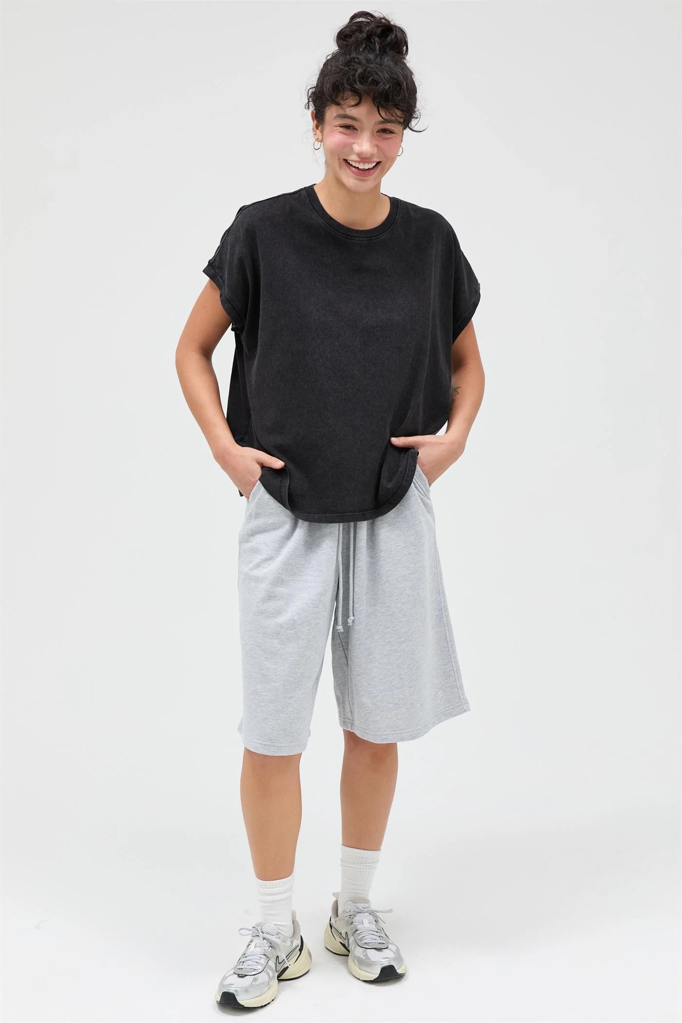 Person wearing a black t-shirt and gray shorts on a white background