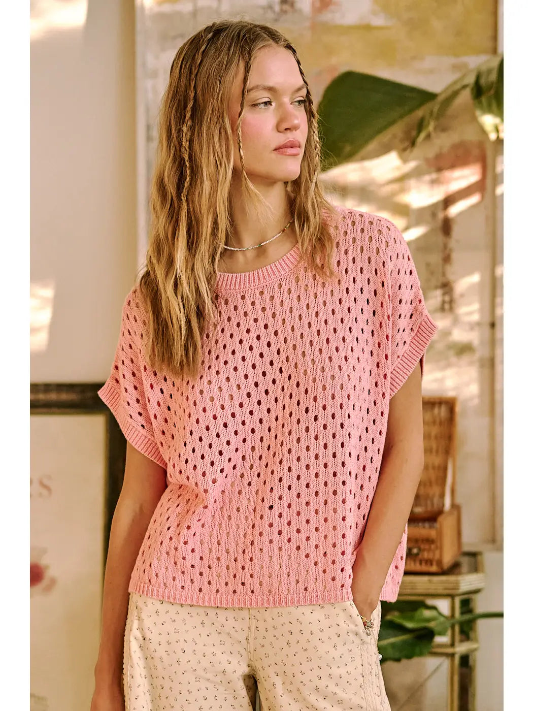 Woman wearing a pink crochet top in an indoor setting