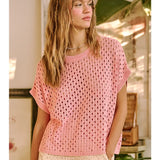 Woman wearing a pink crochet top in an indoor setting