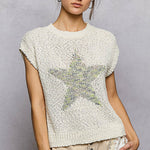 Woman wearing a textured white top with a star design on a plain background